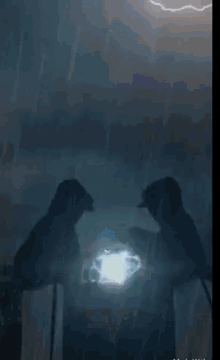 a couple of people standing in the dark with a light coming out of their hands