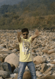 a man wearing a yellow shirt that says ' i love you ' on it stands in a rocky area