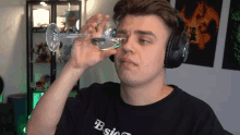 a man wearing headphones is drinking from a glass with the word bsic on his shirt