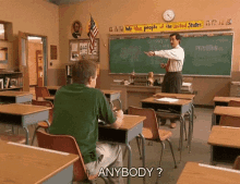 a man sitting at a desk in a classroom with a sign that says " we the people of the united states " on it