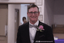 a man in a tuxedo with a pink flower on his lapel is smiling