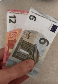 a person is holding two euro bills in their hands