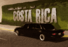 a car is driving past a wall that says costa rica on it