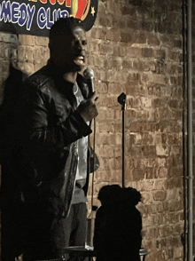 a man stands in front of a microphone in front of a sign that says comedy club