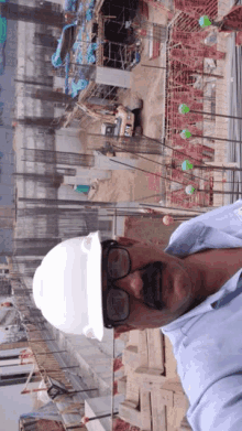 a man wearing glasses and a hard hat is standing in front of a construction site