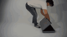 a man in a white shirt and jeans is bending over to pick up something