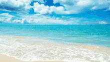 a beach with a blue sky and white clouds and waves crashing on the sand