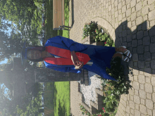 a woman in a blue cap and gown is standing in front of a sign that says ' a ' on it