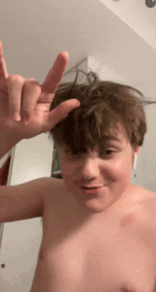 a shirtless boy is making a peace sign with his finger