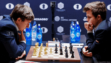 two men are playing a game of chess in front of a sign that says ig capital advisors