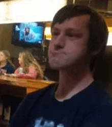 a man is sitting at a table in a restaurant with a tv in the background .