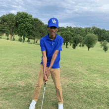 a man wearing a kentucky hat is holding a golf club