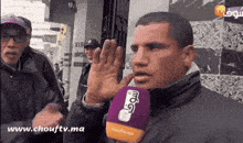 a man talking into a purple microphone that says chouftv.ma