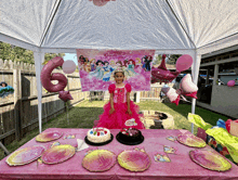 a little girl is standing in front of a birthday table