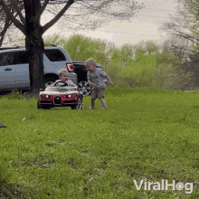 two young boys are playing with a toy car in a grassy field with the words viralhog on the bottom