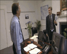 a man in a suit stands in front of a desk with a name plate that says ' robert '