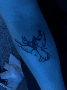 a tattoo of a woman with wings on her arm is glowing in the dark