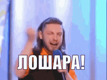 a man singing into a microphone with the words " лошара " written in white letters