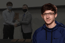 a man wearing a blue nike sweatshirt stands in front of two men