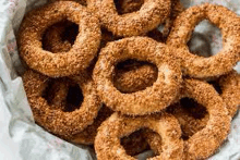 a bunch of sesame seed doughnuts in a basket .