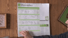 a person is pointing at a calendar that says december