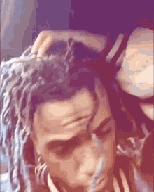 a close up of a person 's head with dreadlocks and a woman 's hand on it .