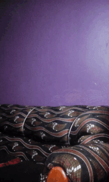 a purple wall is behind a couch with a snake pattern on it