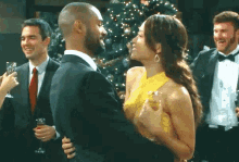 a woman in a yellow dress is dancing with a man in a suit