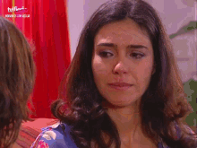 a woman is crying in front of a red curtain that says tvfina