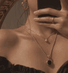 a woman is taking a selfie with her phone while wearing a necklace .