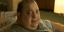 a very fat man with an oxygen tube in his nose is sitting on a bed .