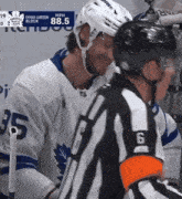 a hockey player wearing a number 35 jersey talks to a referee