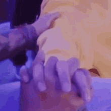 a close up of a person holding another person 's hand with a purple background .