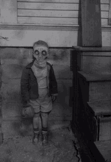 a black and white photo of a child in a halloween costume with a pumpkin