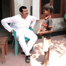 a man is sitting in a chair and talking to a young boy .