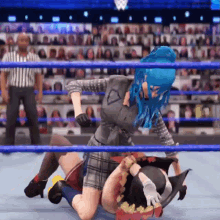 a woman with blue hair is wrestling another woman in a ring .