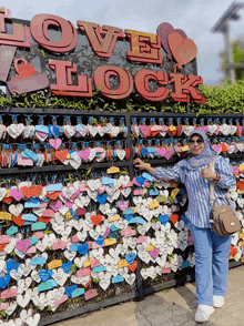 a woman stands in front of a love lock fence