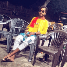 a man wearing a yellow shirt with the word mcm on it sits in a chair