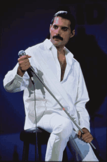 a man singing into a microphone while sitting on a stool