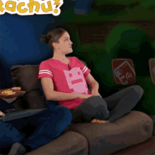 a woman sitting on a couch wearing a pink shirt that says pac-man on it