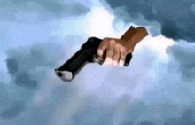 a person is holding a gun in the air in the clouds .