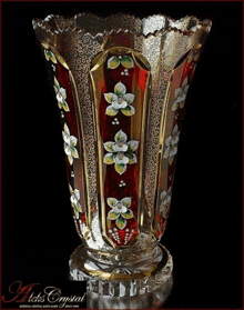 a red and gold vase with flowers painted on it is from a company called aek 's crystal