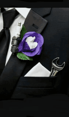 a man wearing a black suit has a purple flower and a spark plug in his pocket