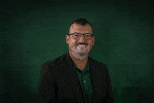 a man with glasses and a green shirt is smiling