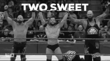 three men are standing in a wrestling ring with their arms in the air and the words `` two sweet '' written above them .