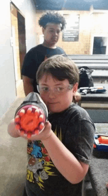 a boy wearing a shirt that says ' simpson ' on it is holding a toy gun