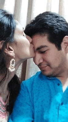 a woman kissing a man on the forehead with a blue shirt on