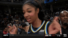 a female basketball player is giving a high five in front of a crowd with the espn logo in the corner