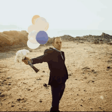 a man in a suit holds a bouquet of flowers and balloons in his hand