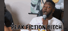 a man speaking into a microphone with the caption peak fiction bitch